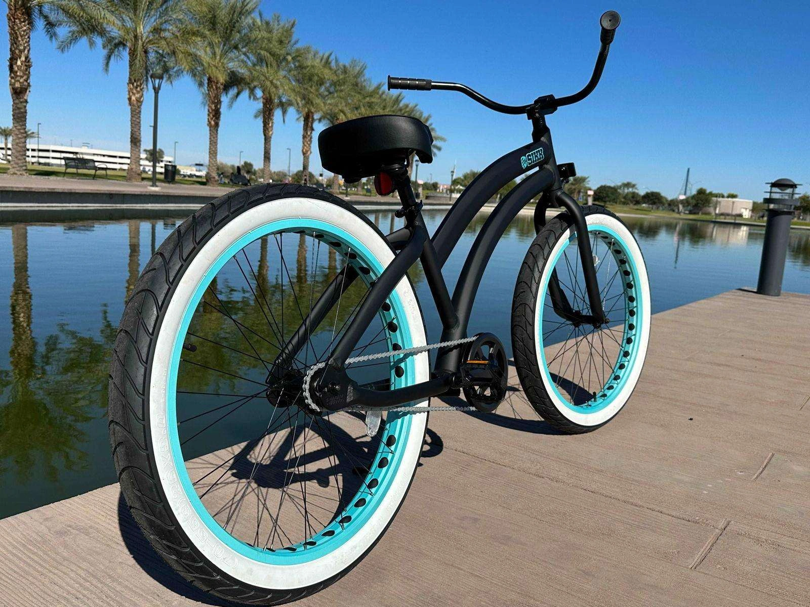 Damesfiets SIKK Wide Ride Zwart Aluminium Singlespeed met Teal Velgen & Witte Banden.